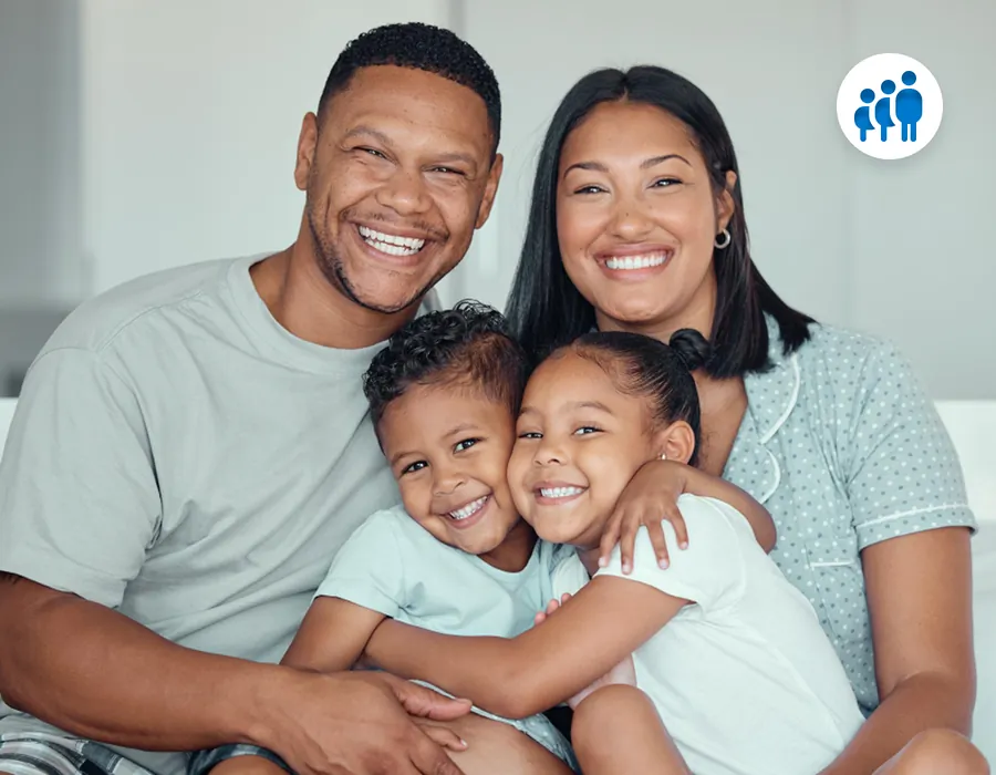 A smiling family of four hugging on the sofa